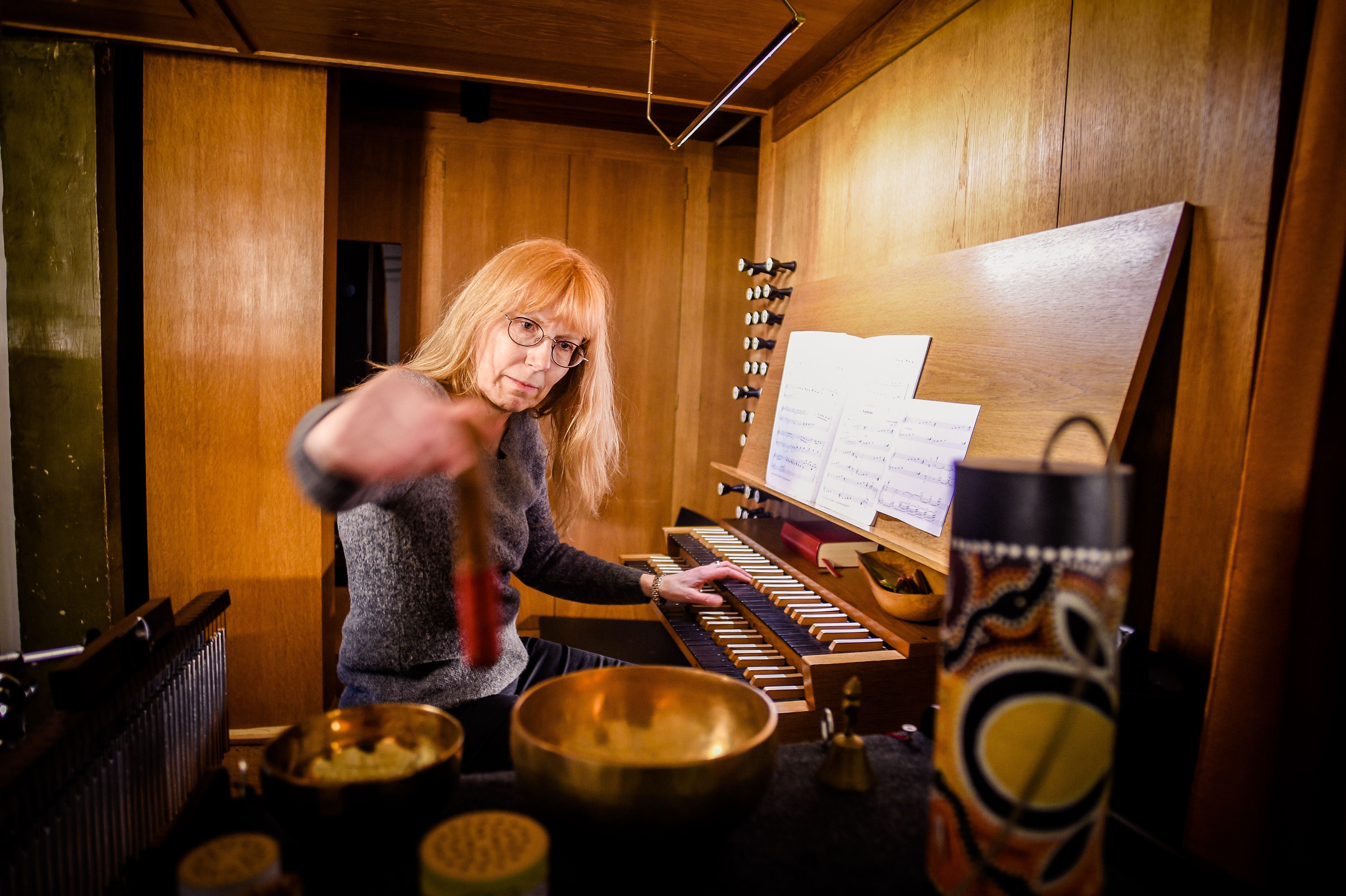 Unsere Kantorin María Cristina Witte sitzt auf der Orgelbank und spielt an daneben stehenden Klangschalen.